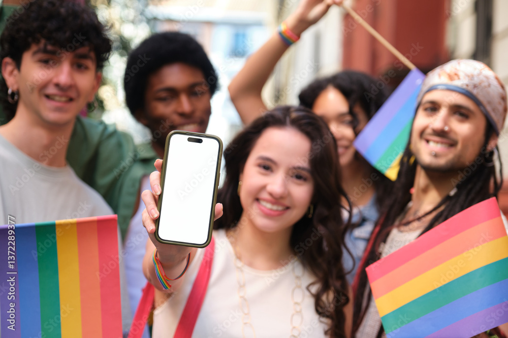 Group of smiling multi ethnic friends celebrating gay pride holding rainbow flags and showing smartphone with blank screen