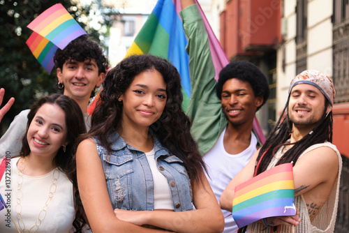 Group of young multi ethnic activists holding rainbow flags celebrating gay pride during street parade