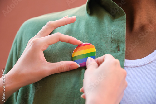 Obraz na płótnie Hands pinning rainbow badge on green shirt, lgbtq plus concept w salonie