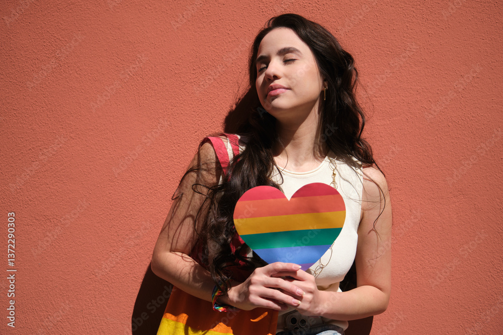 Young woman holding rainbow heart celebrating LGBT pride month