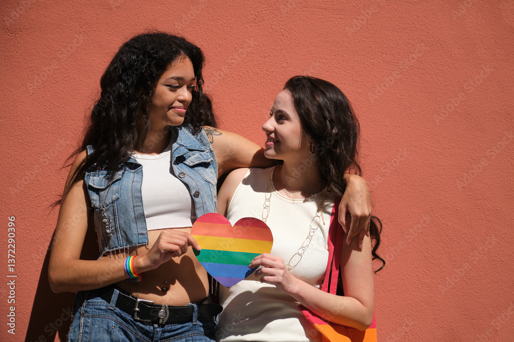 Two young women showing their love and support for LGBT rights with a rainbow heart