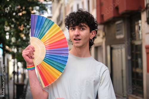 Obraz na płótnie Young man holding rainbow hand fan celebrating LGBT pride in the city w salonie