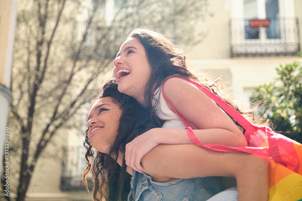 Two cheerful lgbt students having fun piggybacking in the city on a sunny day