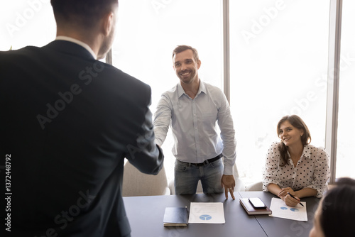 Behang Two smiling millennial businessmen, partners, shareholders shaking hands before