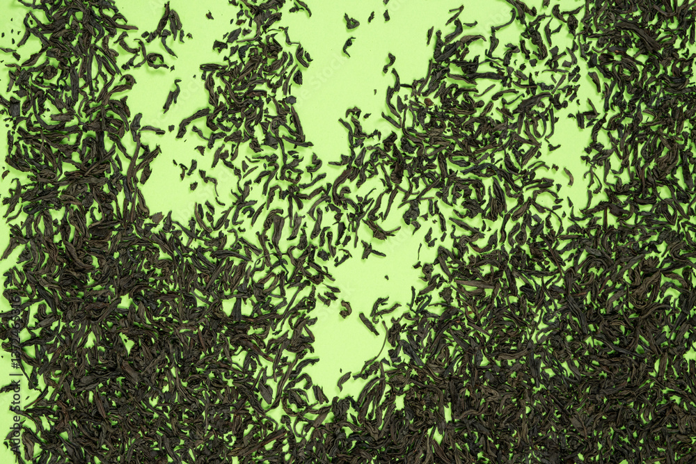 Fototapeta premium Loose black tea scattered on green background