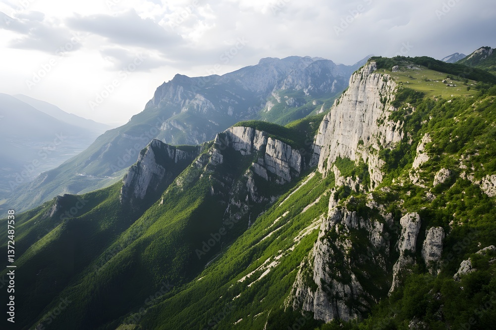 Naklejka premium Rugged mountain range; steep, green forested slopes under cloudy sky