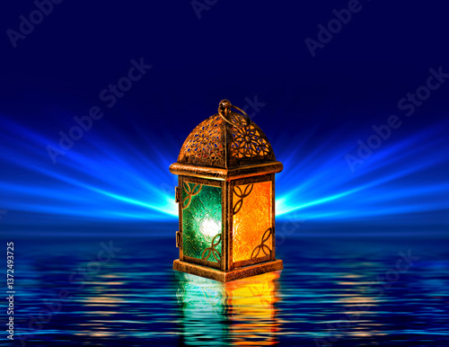 Slika na platnu Glowing Ramadan lantern with intricate metal patterns reflecting on water, illuminated by warm and cool lights, against a deep blue radiant background