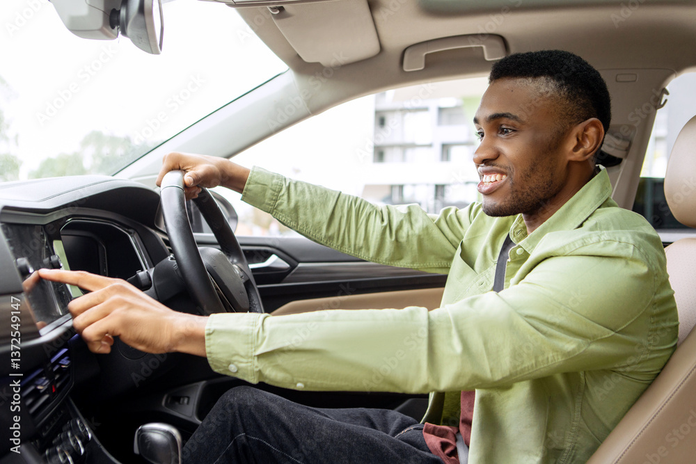 Obraz premium Transport and modern technology concept. Cheerful black man searching for route using navigation system on car dashboard screen