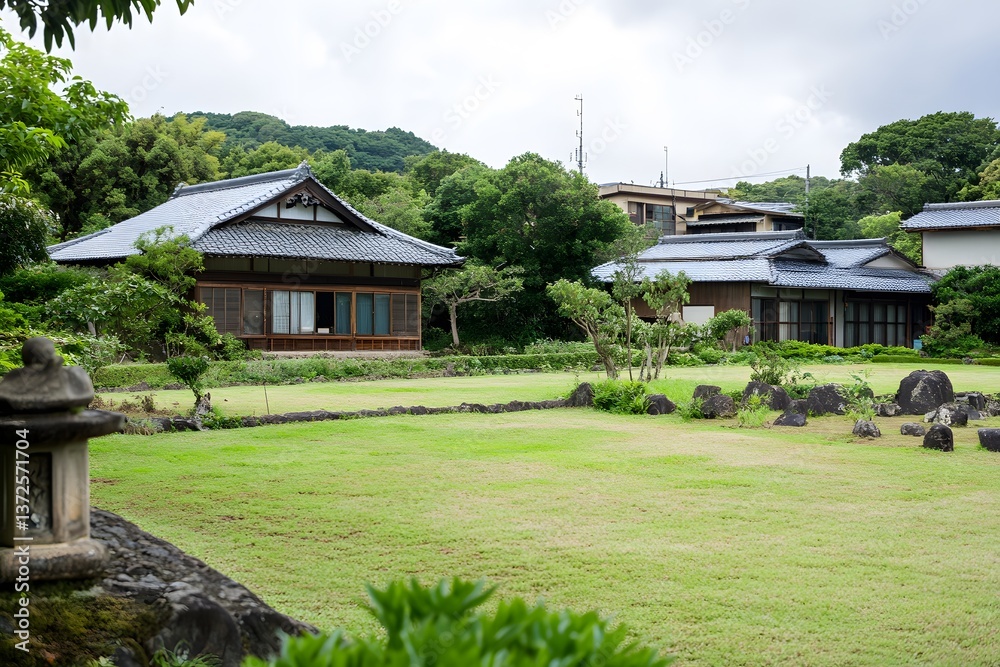 Fototapeta premium Traditional Japanese homes surround bright grassy lawn and stone garden