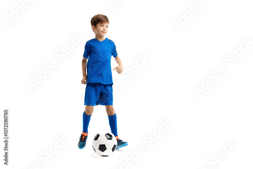 Sporty young boy in blue sport outfit playing with classic soccer ball over white background