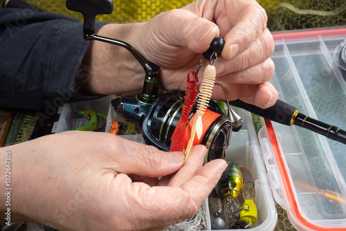 Sport fishing equipment on a table in a studio composition, against a background of a net. A fisherman's hands check the tackle for use.