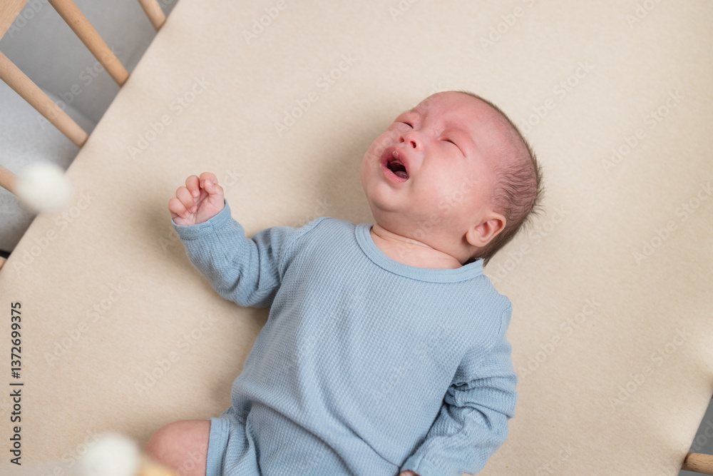 Infant crying while lying on bed