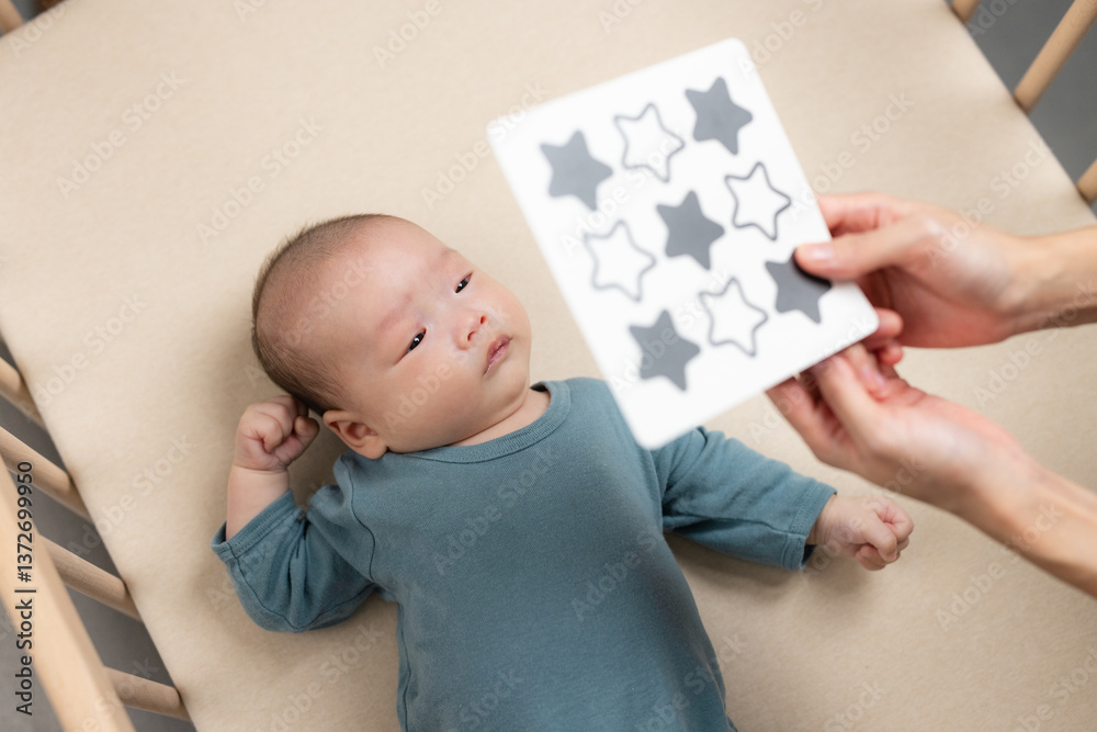 Newborn baby watching black and white pattern card in crib