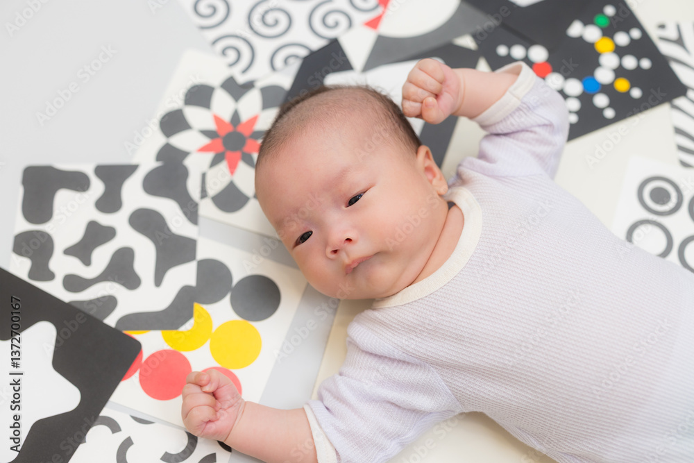 Newborn baby lying with high contrast cards