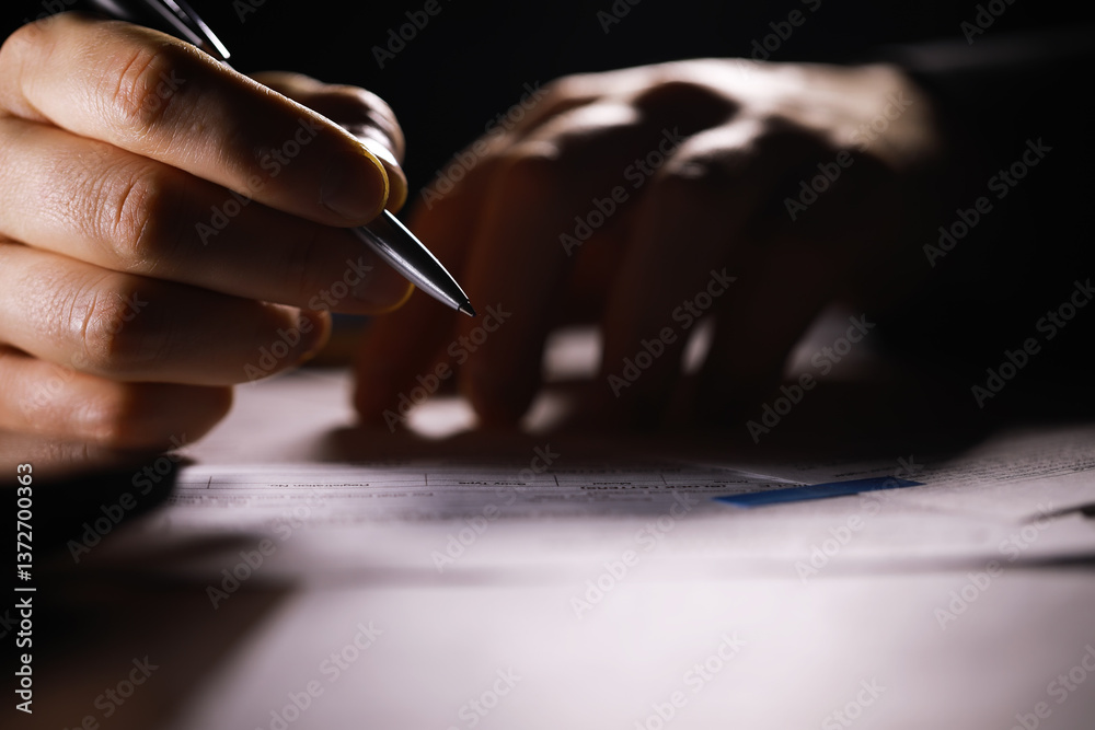 Close-Up of Hand Writing on Document with Pen Under Dim Light