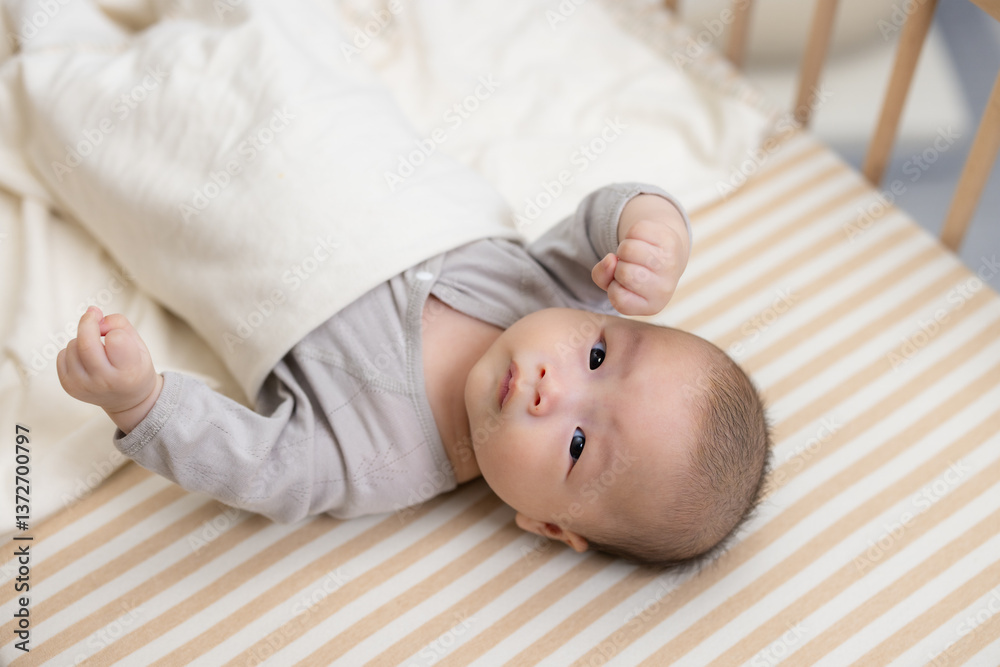 Cute baby lying in wooden crib looking up