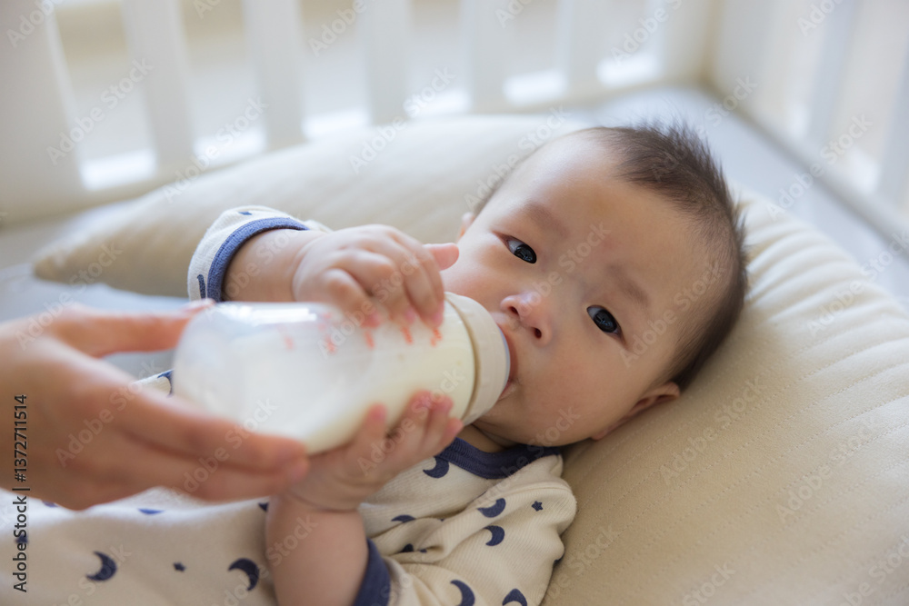 Mother holding bottle feeding cute baby