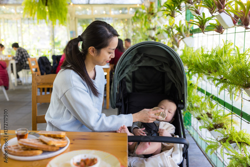 Mother Feeding Baby With Milk Bottle Indoors