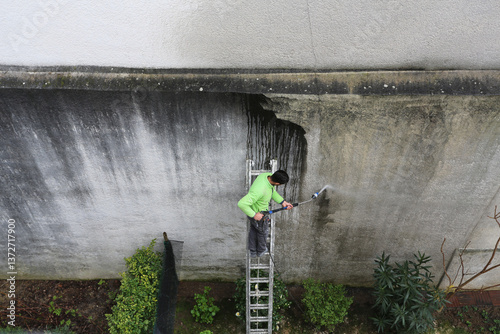 Homme qui nettoie un mur au jet haute pression