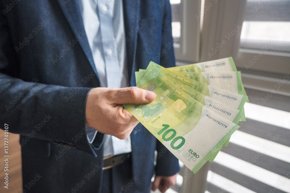 Man in suit holding euro banknotes, business.