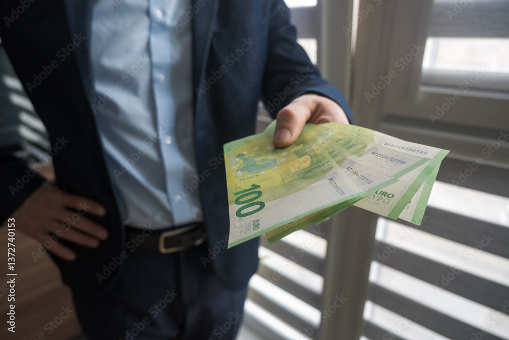 Man in suit holding euro banknotes, business.