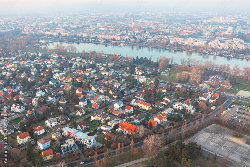 Aerial image reveals Vienna captivating blend of urban landscape with rows of residential houses and Danube river flowing through city. Architecture reflects the city charm, framed by natural elements