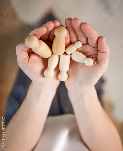 Close-up of female hands with wooden figures in open palms. Small wooden figures, the concept of family, protection, love and care. Conceptual Family Photography