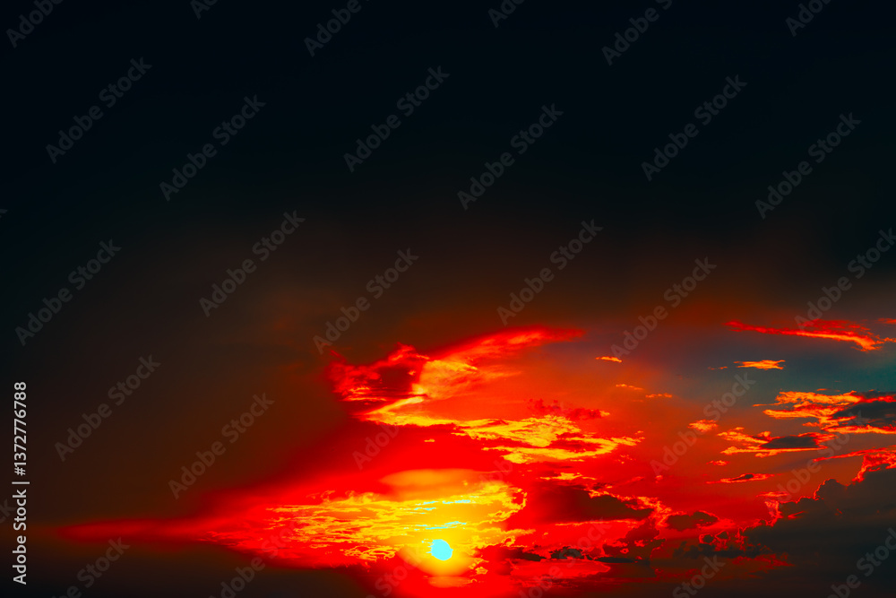 Mesmerizing sunset with sun descending near horizon, bathing sky in warm glow. Dramatic clouds painted in fiery shades of red, orange, create vivid and breathtaking contrast against deepening dusk
