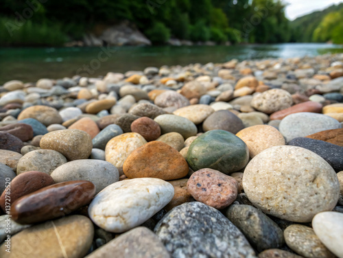 Colorful pebbles on the rocky shore of Lake Soveropoulou in summer, forest and river in the background