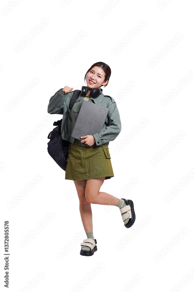 Portrait of Asian female student wearing backpack, headphones, fashionable clothes, holding laptop, posing dynamically on white background Portrait of Asian female student wearing backpack, headphones, fashionable clothes, holding laptop, posing dynamically on white background