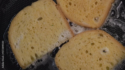 Croutons of bread are fried in a frying pan.