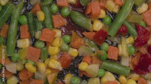 A mixture of frozen vegetables lies in a frying pan, top view.