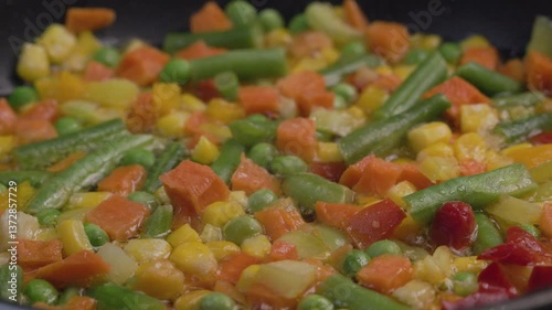 A mixture of frozen vegetables lies in a frying pan, top view.