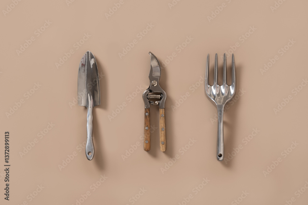 Various gardening hand tools on beige background. Spring gardening. Concept season work. Wood and metal small sized hand cultivator. Top view.
