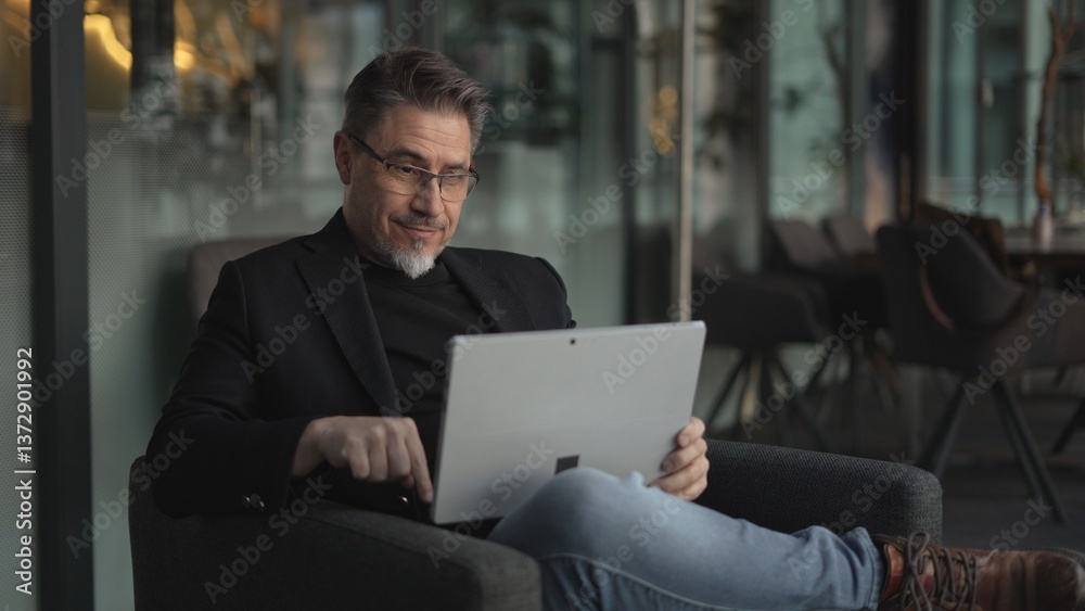 Happy middle age businessman using laptop computer in office. Older casual man working online on terrace of cafe, smiling. Happy middle age businessman using laptop computer in office. Older casual man working online on terrace of cafe, smiling.