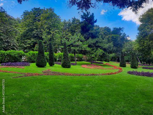 Landscape with spruce trees, flower paths, and green lawns in the park