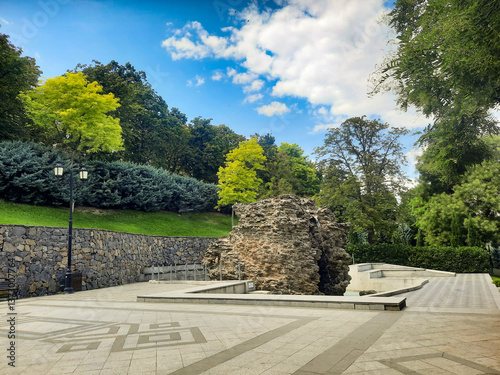 A huge stone in the park among green trees