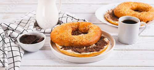 Bagel sandwich with butter and grated chocolate on a plate on a table web banner
