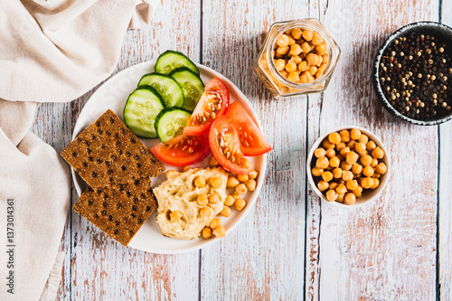 Obraz na płótnie Hummus, chickpeas, tomato, cucumber, grain crackers on a plate on the table top view w salonie
