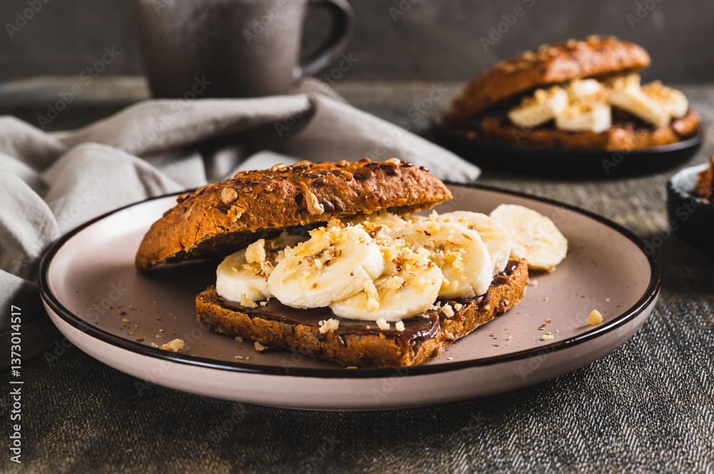 Sweet sandwich with chocolate butter, banana and nuts on a plate on the table
