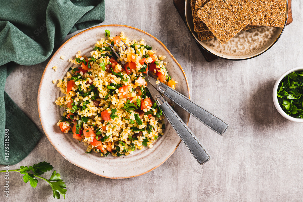 Tabbouleh salad with bulgur, tomato and parsley on a plate on the table top view