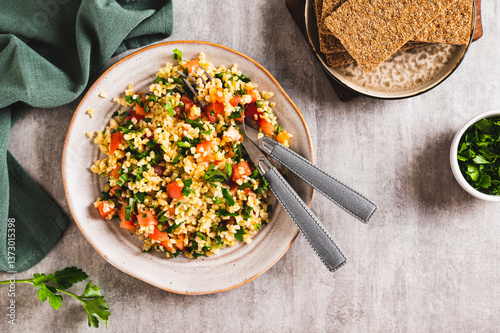 Tabbouleh salad with bulgur, tomato and parsley on a plate on the table top view