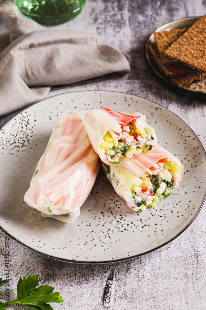 Spring rolls with crab meat, cucumber and herbs on a plate on the table vertical view