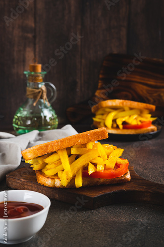Obraz na płótnie Fried toasts with french fries and tomato on a board on the table vertical view w salonie