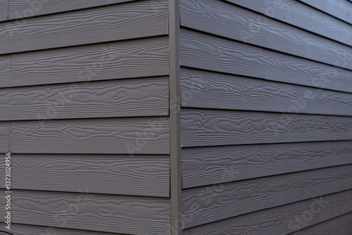 Obraz na płótnie The corner of a house features gray horizontal siding with a wood grain texture, emphasizing clean lines and modern architectural design. w salonie