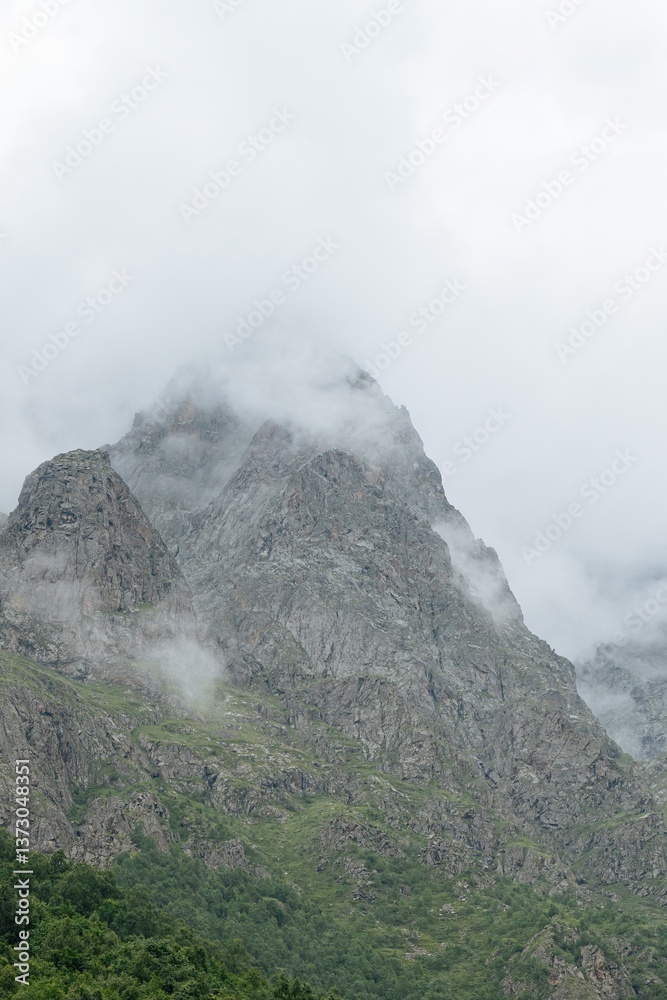 Misty peaks rise dramatically, cloaked in clouds, while verdant valleys lie below in the enchanting landscapes of North Ossetia, showcasing nature's raw beauty and mystery Misty peaks rise dramatically, cloaked in clouds, while verdant valleys lie below in the enchanting landscapes of North Ossetia, showcasing nature's raw beauty and mystery