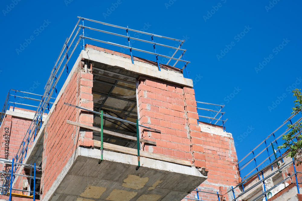 Obraz premium Modern brick building construction against clear blue sky in urban development