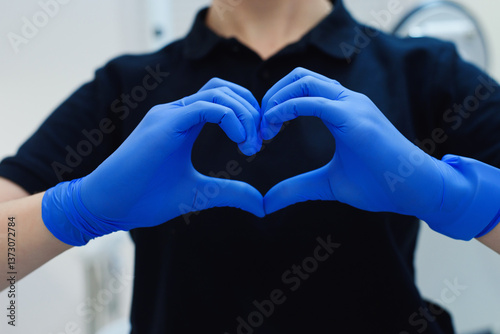 Female hands of dental assistant in latex gloves show a heart symbol. Showing care support with love to the patient