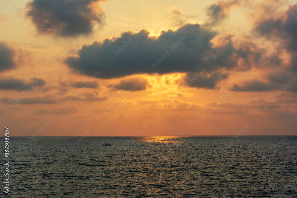 Fototapeta premium Sunset over calm sea with fishing boat