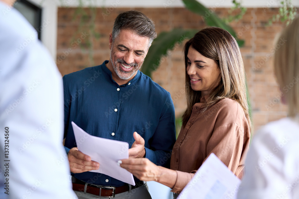 Fototapeta premium Happy older company manager having discussion with business team planning project strategy meeting in modern office. Diverse corporate leaders discussing financial documents standing in office.